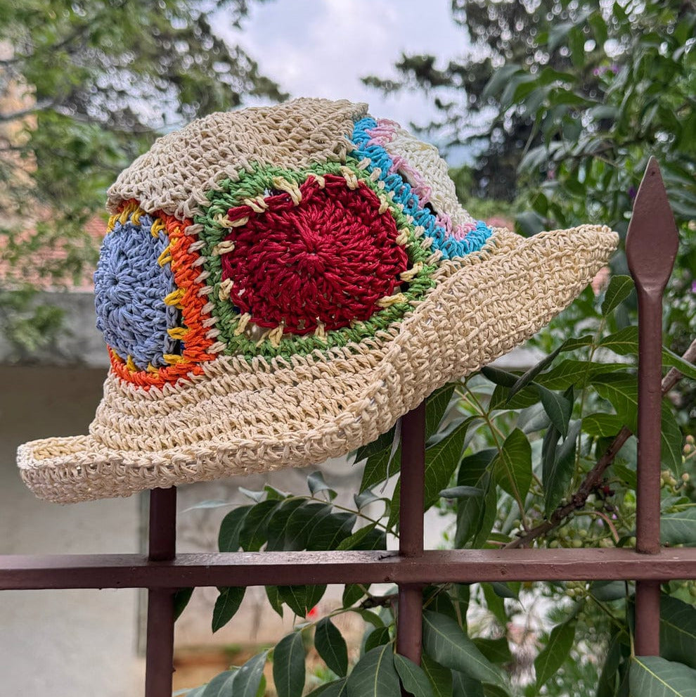 Colorful crochet-patterned hat on a metal railing with greenery in the background
