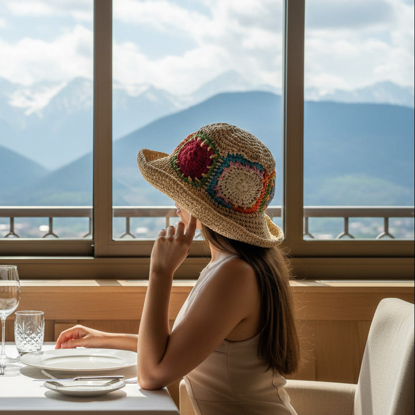 Colorful crochet-patterned hat on a metal railing with greenery in the background
