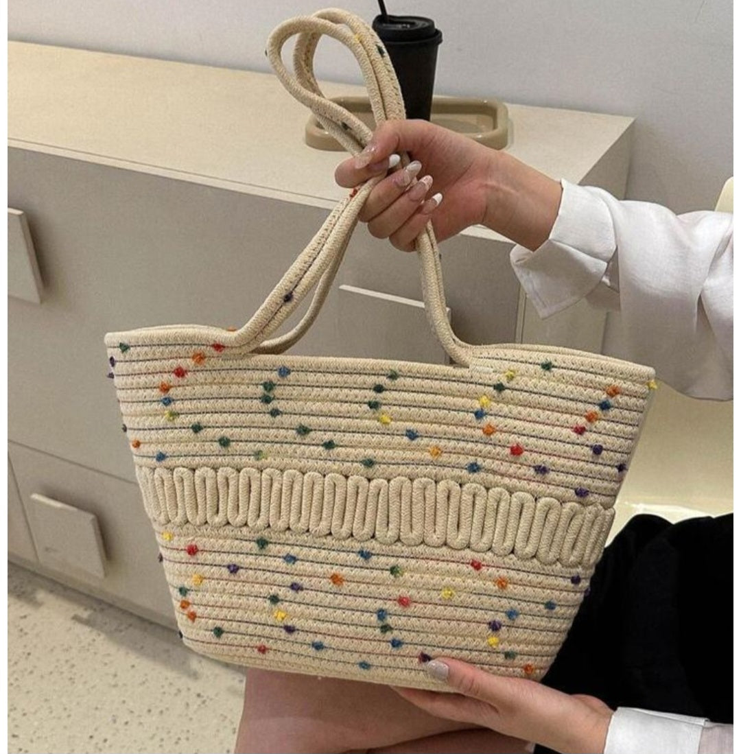 Hand holding a woven bag with colorful dots in an indoor setting